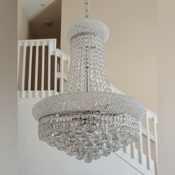 Crystal chandelier hanging in a room with a staircase in the background