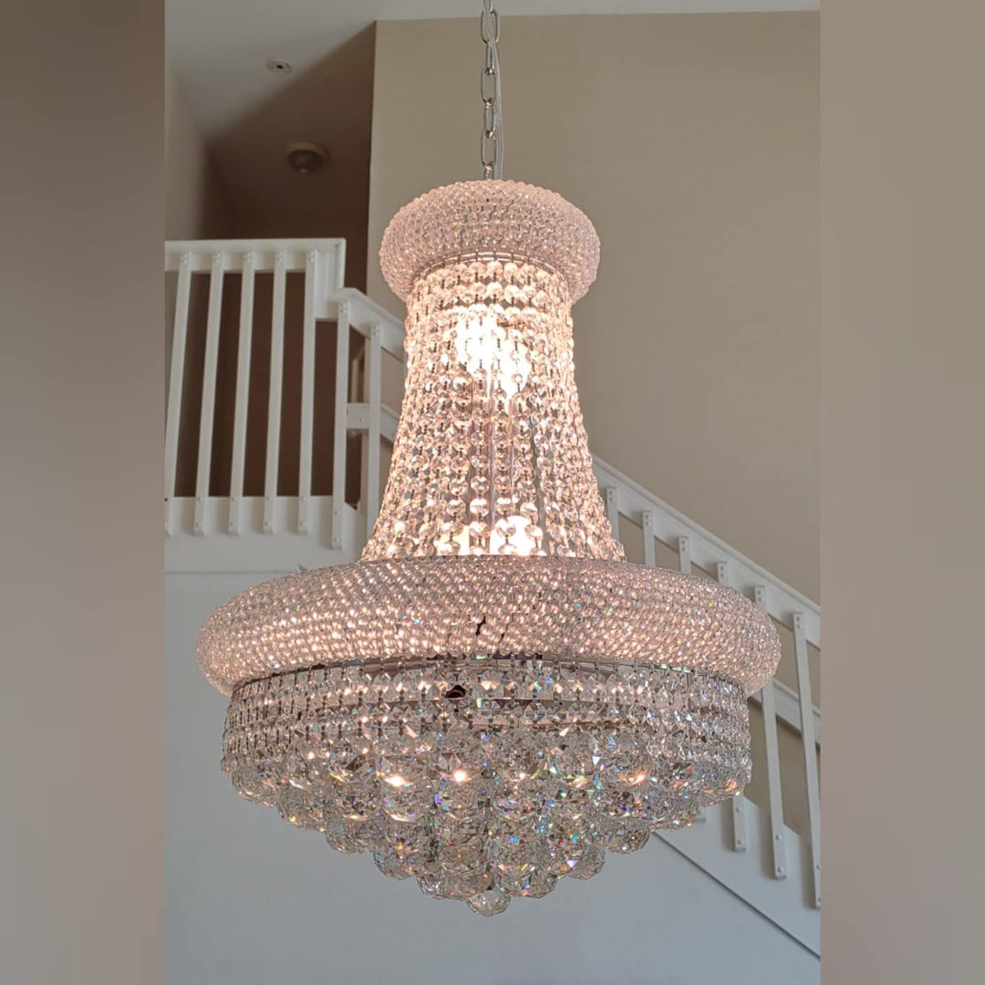 Crystal chandelier hanging in a room with a staircase in the background