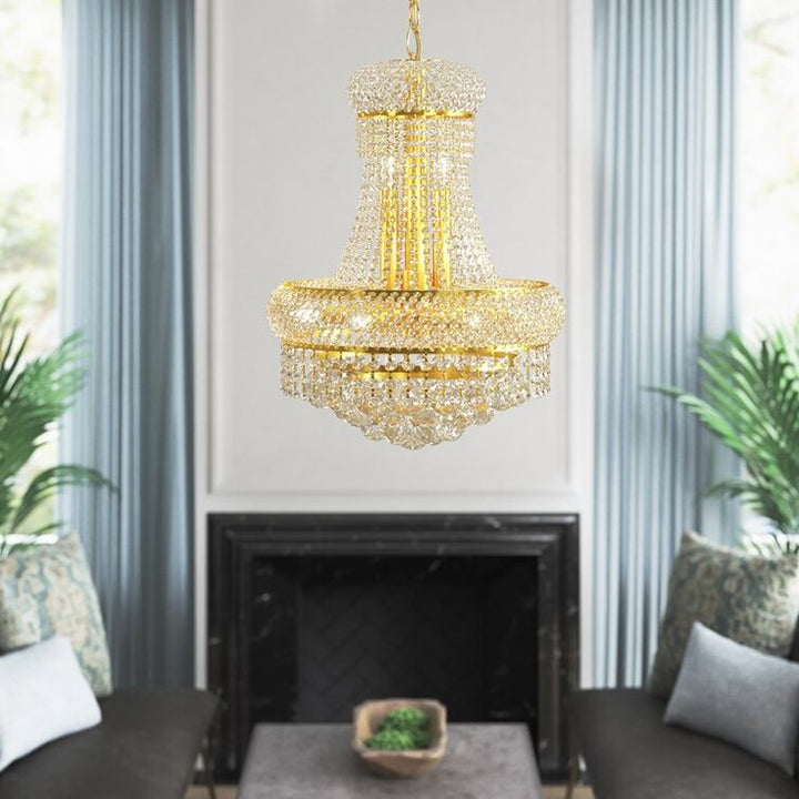 Gold chandelier hanging above a fireplace in a room with plants and furniture.