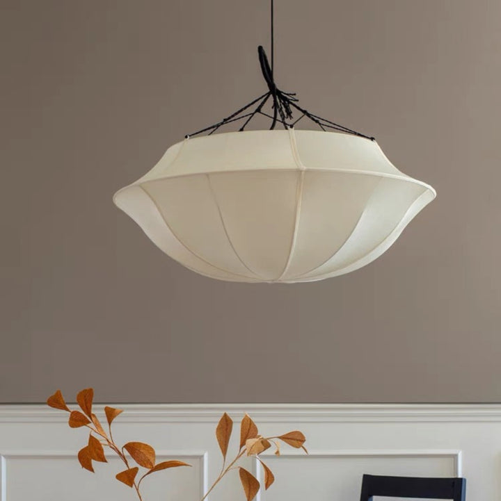Pendant light fixture hanging above a table with decorative items against a plain wall.