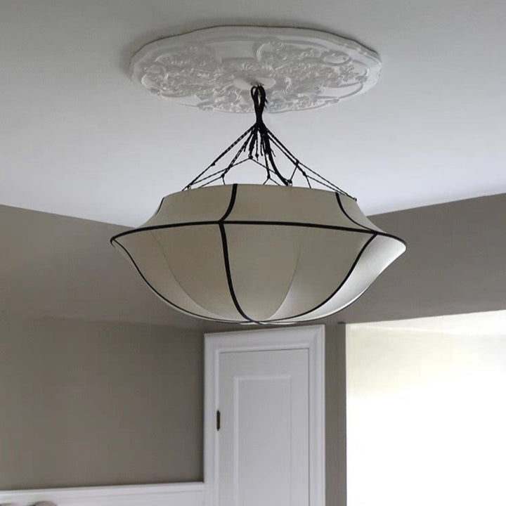 Ceiling light fixture in a bedroom setting with neutral walls and furniture.