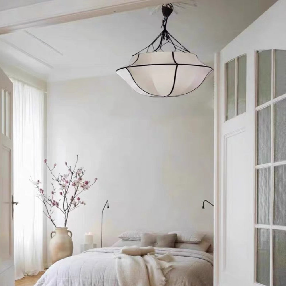 Neatly arranged bedroom with a bed, lamp, and vase on a wooden floor.