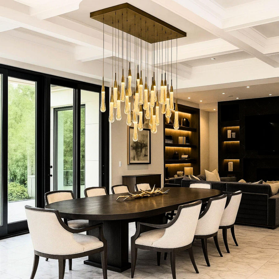 Modern dining room with a large chandelier, dark wooden table, and white chairs.
