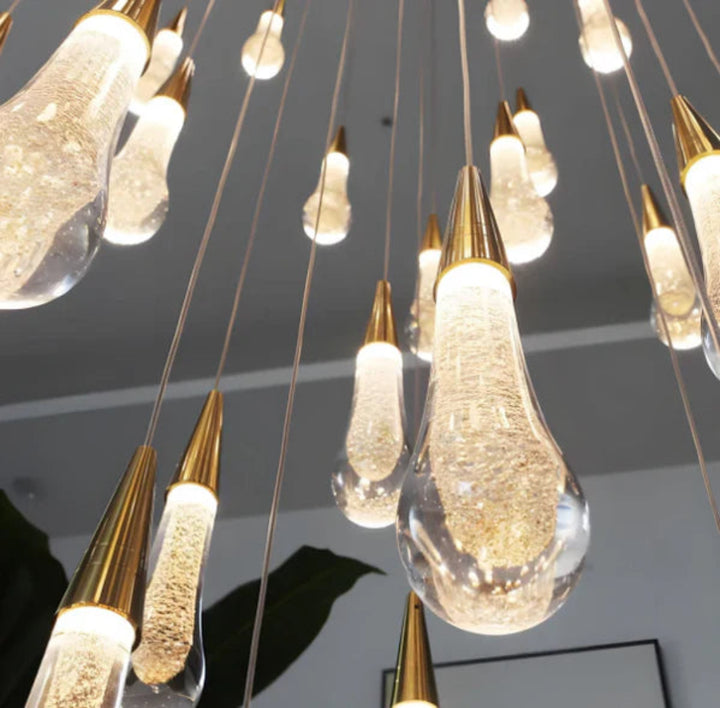 Modern chandelier with gold and clear glass pendant lights on a dark ceiling.