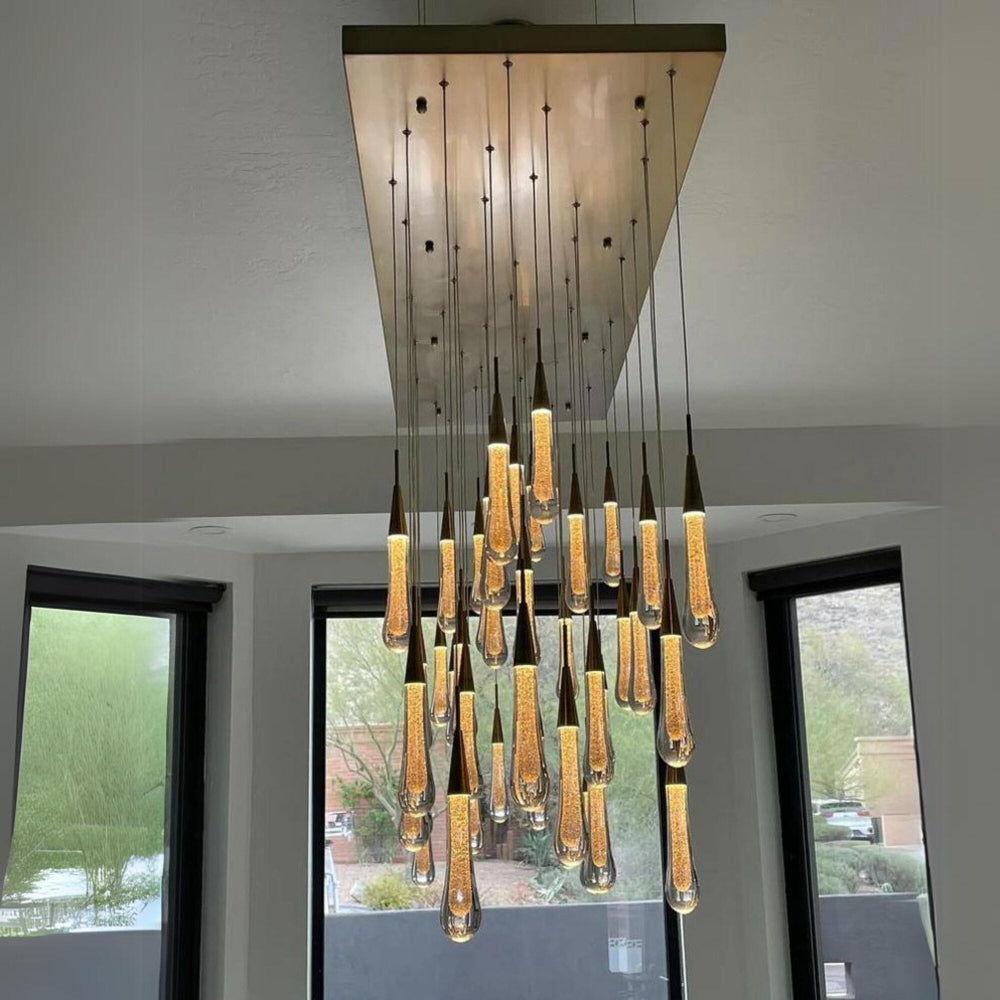 Modern chandelier hanging from a ceiling with large windows in the background