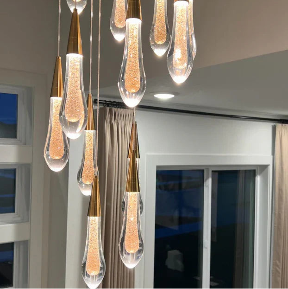 Modern pendant light fixture with clear glass shades and gold accents in a room setting.