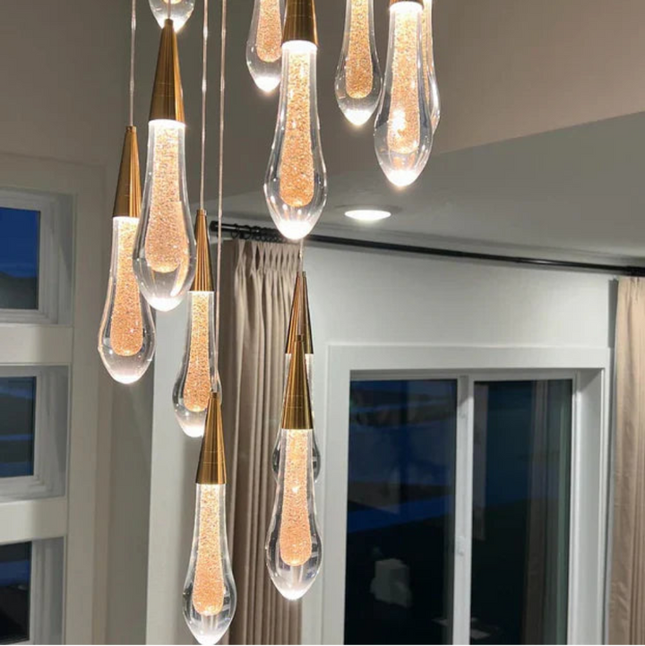 Modern pendant light fixture with clear glass shades and gold accents in a room setting.
