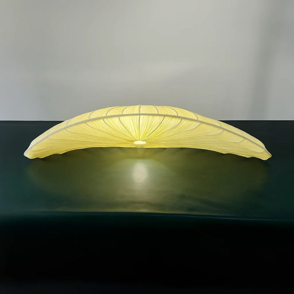 Yellow wing-shaped lamp on a dark surface with a gray background