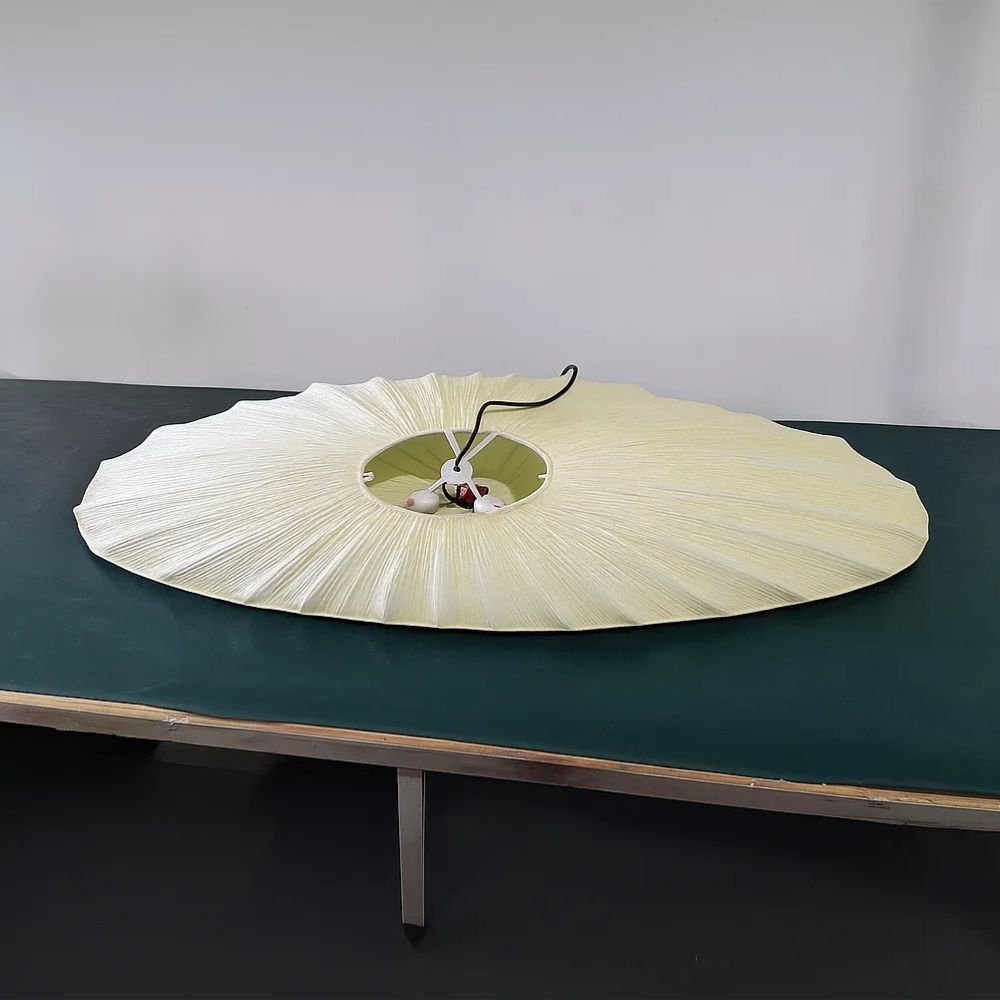 Large white parasol on a dark green table against a plain background
