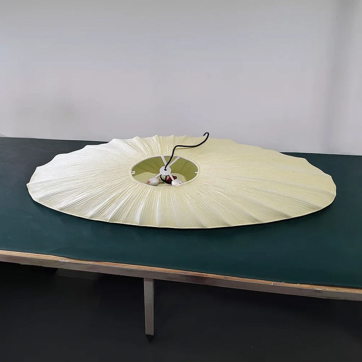 Large white parasol on a dark green table against a plain background