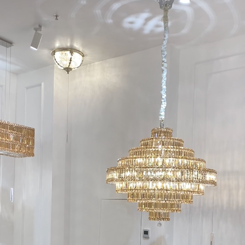 Chandelier hanging in a room with white walls and ceiling lights.