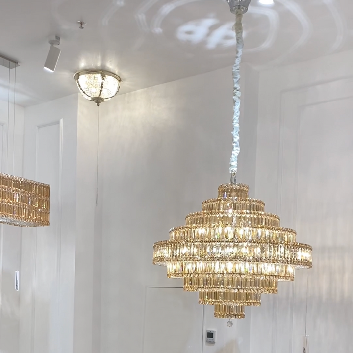 Chandelier hanging in a room with white walls and ceiling lights.