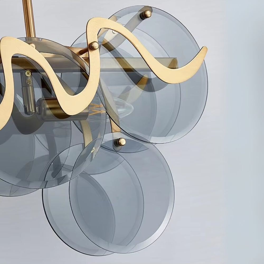 Modern chandelier with gold fixtures and clear glass shades on a light gray background