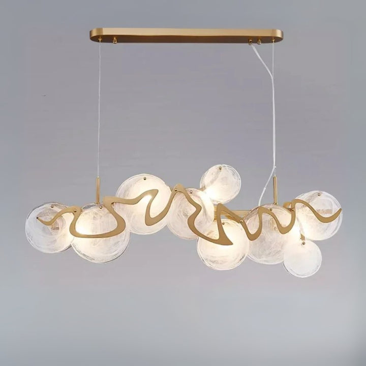 Modern chandelier with glass globes and gold accents on a gray background