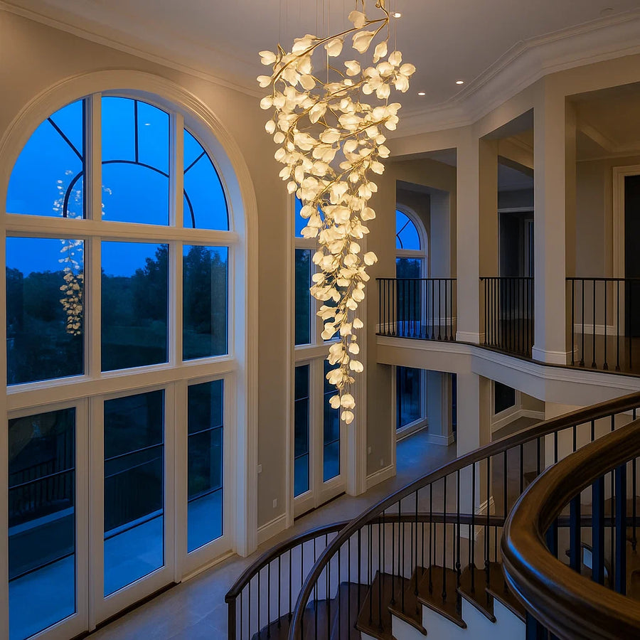 Luxurious interior with a chandelier hanging in a grand room with large windows and a staircase.