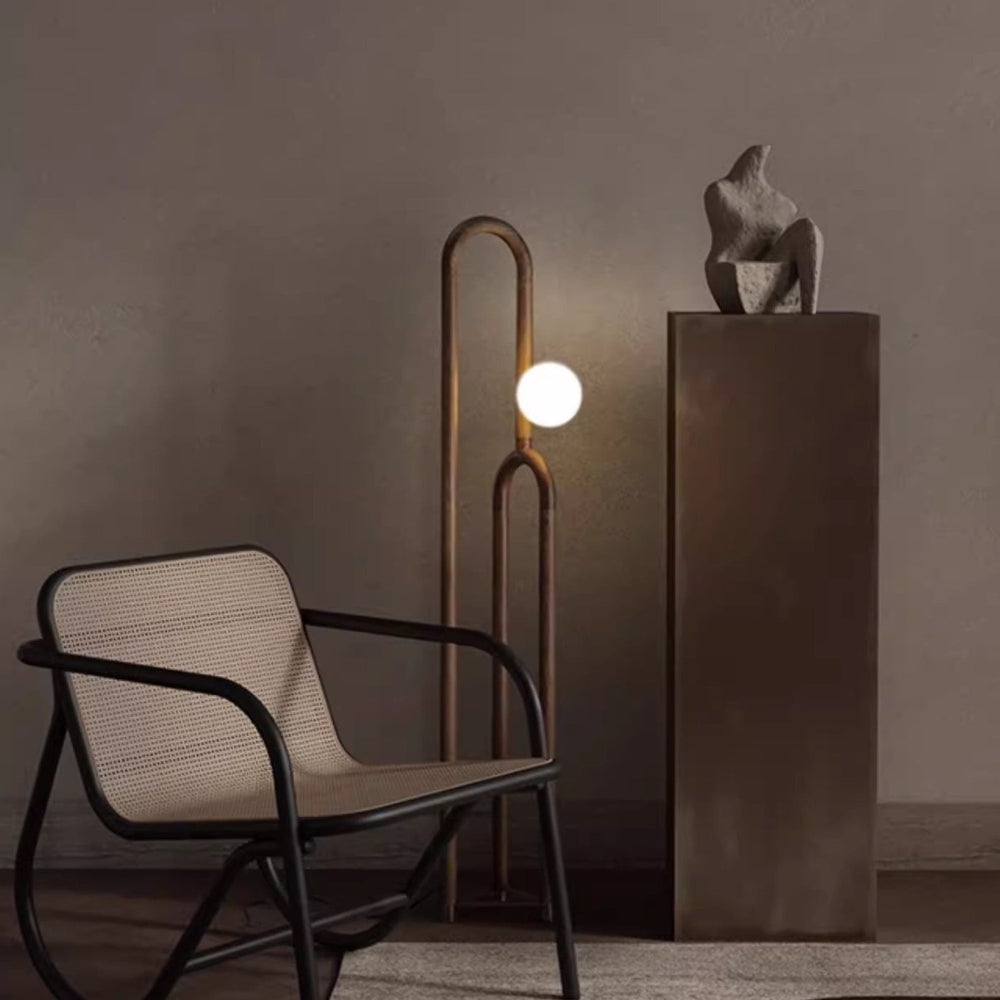 Modern chair with a floor lamp and sculpture in a dimly lit room