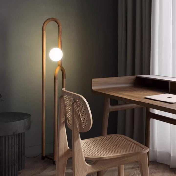 Wooden floor lamp and chair in a room with a desk and window.