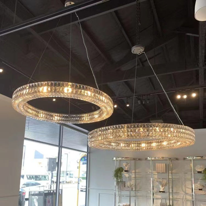 Two crystal chandeliers hanging above a modern dining table in a well-lit room.
