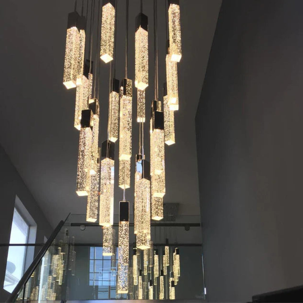 Modern chandelier hanging from a ceiling in a room with a staircase.