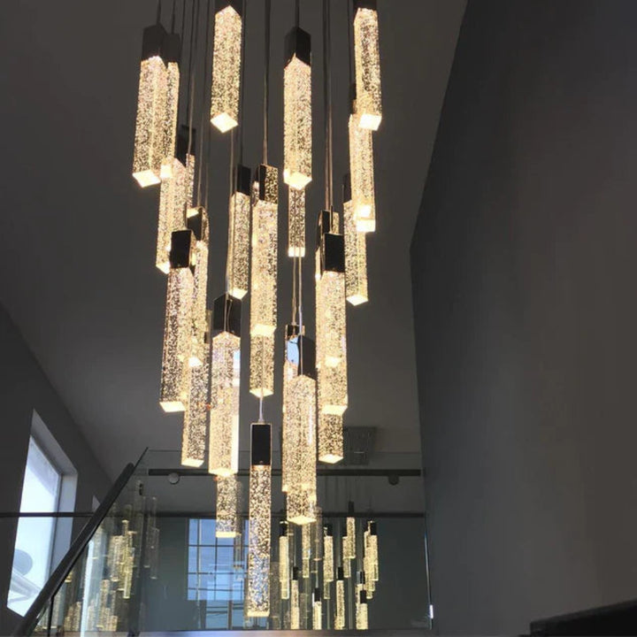 Modern chandelier hanging from a ceiling in a room with a staircase.