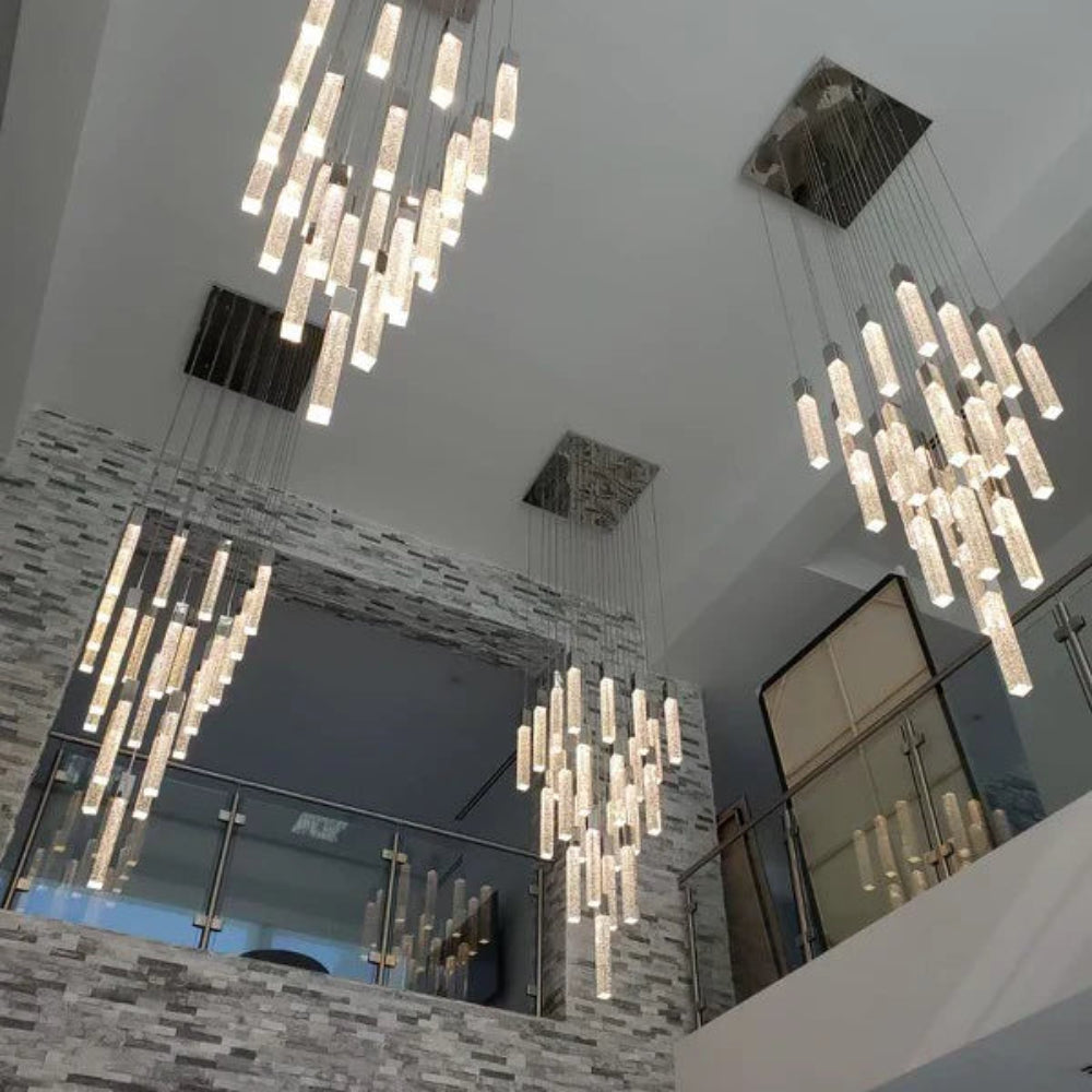 Two Modern Squatu chandelier hanging from a ceiling in an indoor setting with stone walls and mirrors.