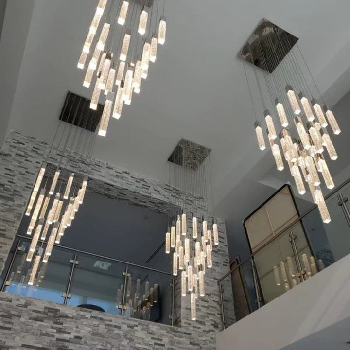 Two Modern Squatu chandelier hanging from a ceiling in an indoor setting with stone walls and mirrors.