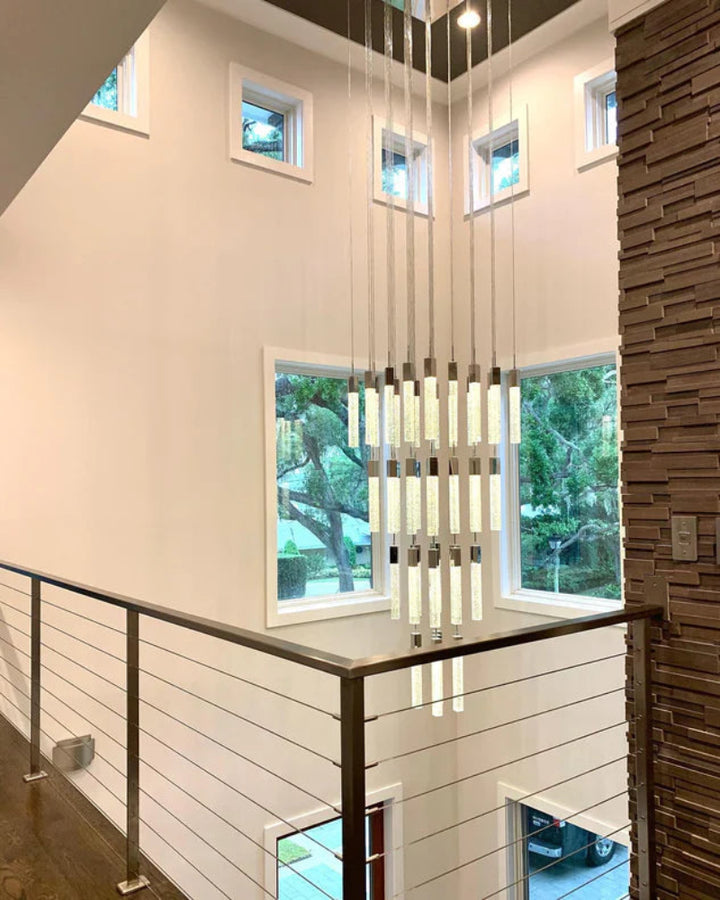 Modern interior with a staircase, glass railing, and large windows.