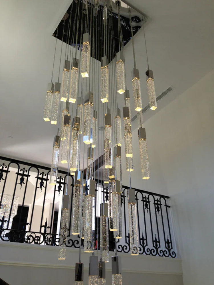 Chandelier hanging from a ceiling with a decorative railing in the background