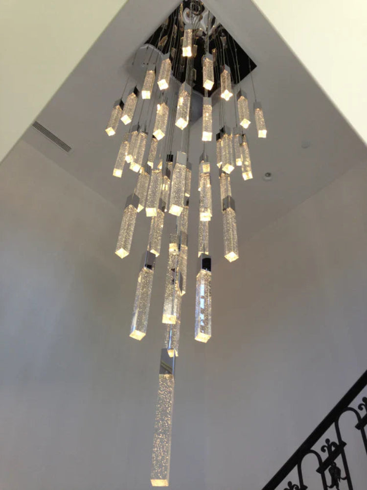 Chandelier hanging from a ceiling with a staircase in the background