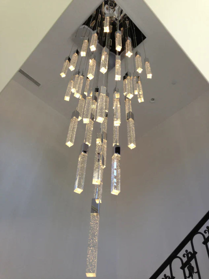 Chandelier hanging from a ceiling with a staircase in the background