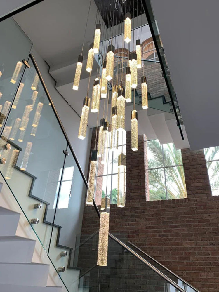 Modern chandelier hanging in a staircase with large windows in the background