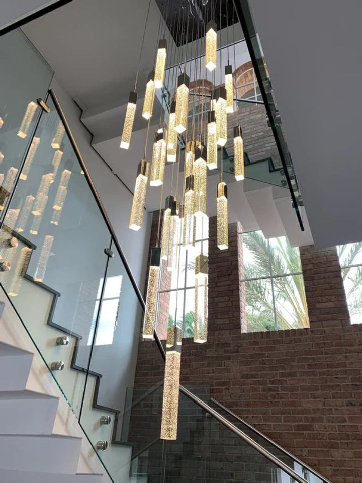 Modern chandelier hanging in a staircase with large windows in the background