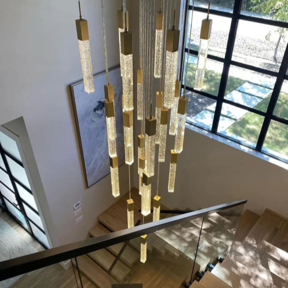 SQUATU Crystsal Pendant Lighting. Modern chandelier hanging above a staircase with a window in the background